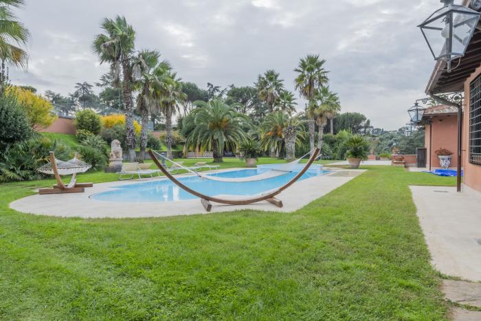 Piscina circondata da palme e verde in una villa a Roma