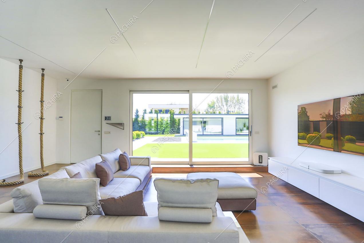 Salotto con corde pendenti dal soffitto, divano di design e ampie vetrate