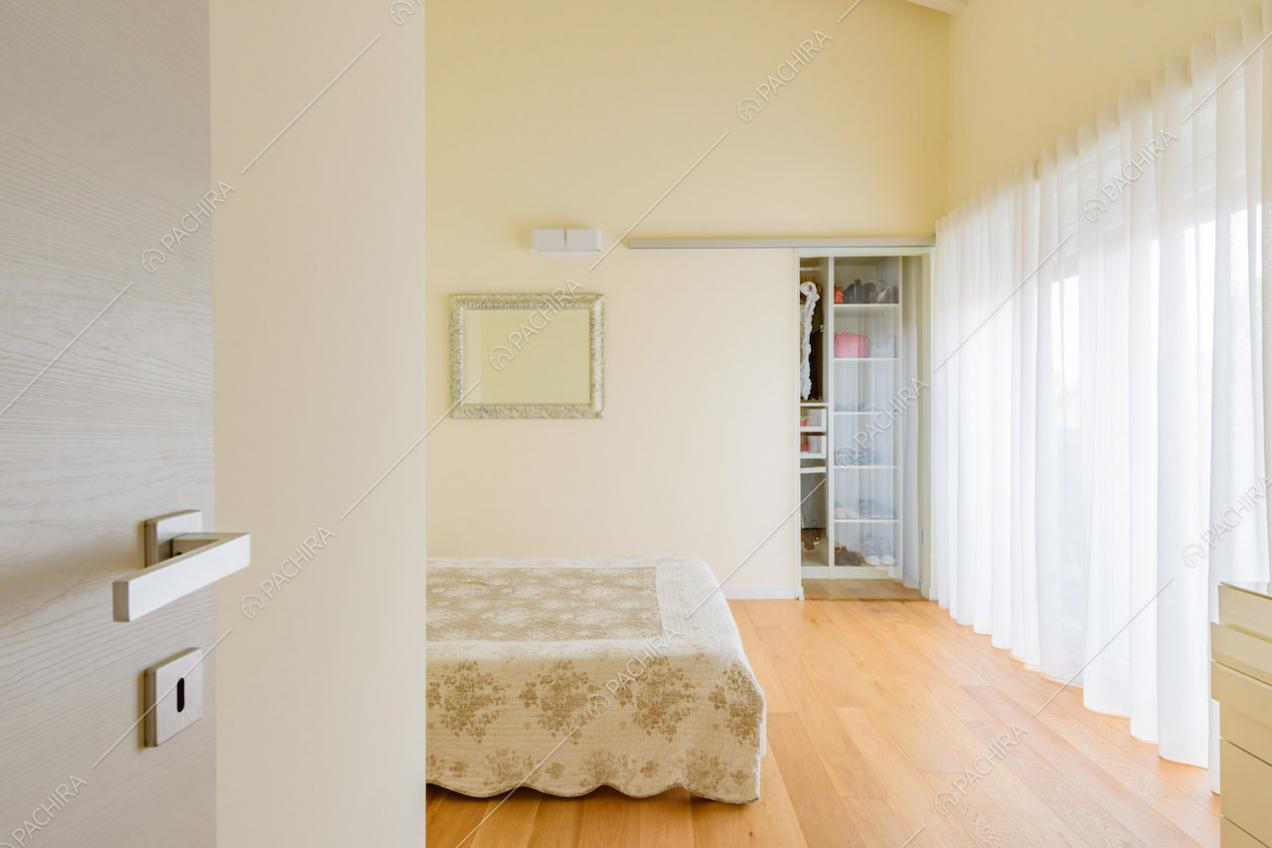 Pavimento in parquet, vetrate, pareti gialle e cabina armadio nella camera
