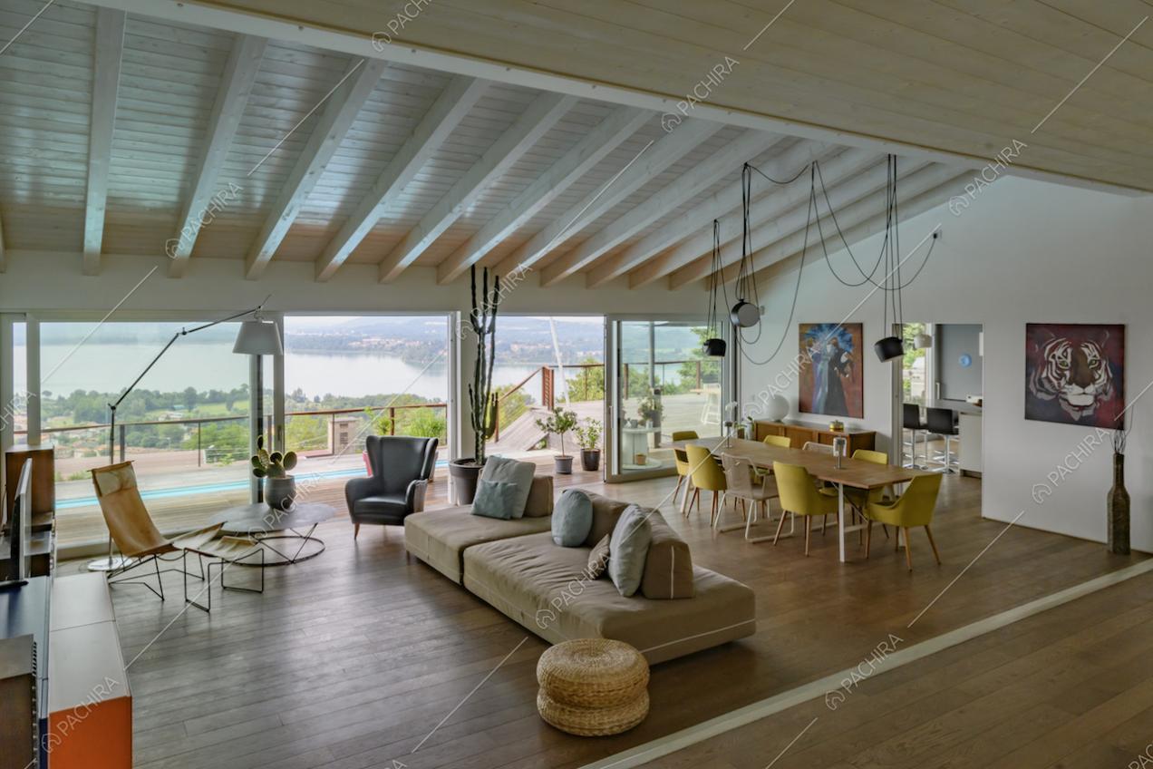 Luminosa sala dalle pareti bianche con divano e tavolo da pranzo e soffitto bianco con travi in legno a vista