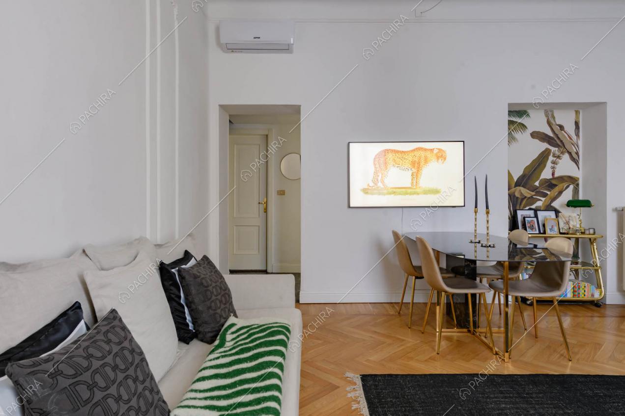 Divano bianco nel luminoso salotto con pavimento in parquet e carta da parati