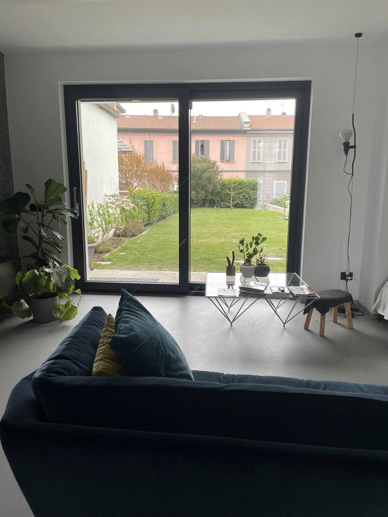Dal divano blu in velluto vista sul giardino attraverso la porta-finestra scorrevole