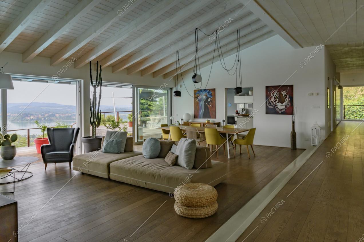 Corridoio rialzato e sala con pavimento in parquet, soffitto con travi in legno a vista e vetrate