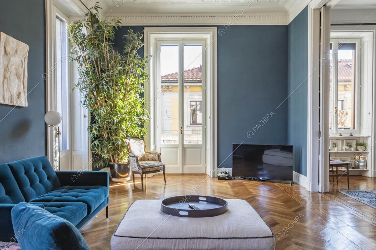 Luminoso salotto con pavimento in parquet a spina di pesce, pareti blu e boiserie sul soffitto