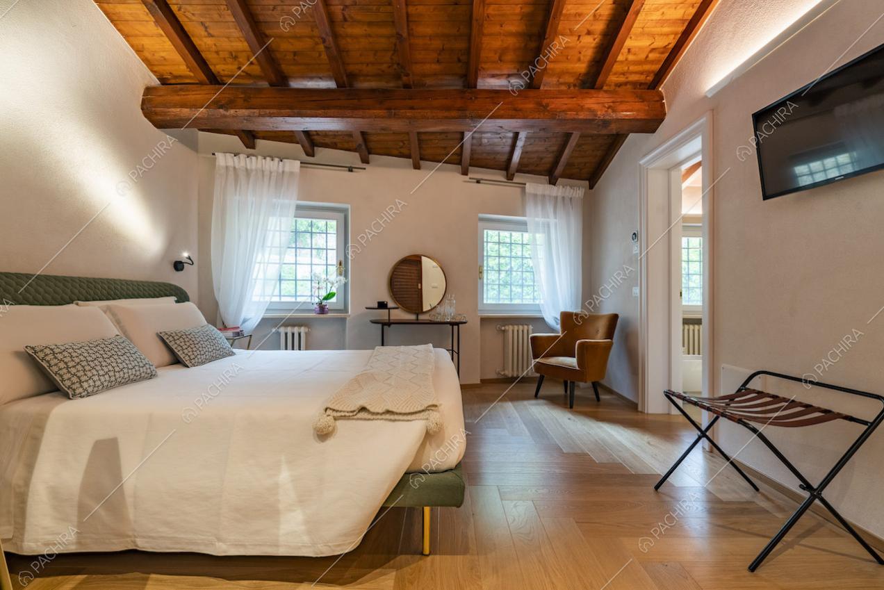 Camera da letto con due finestre e travi sul soffitto