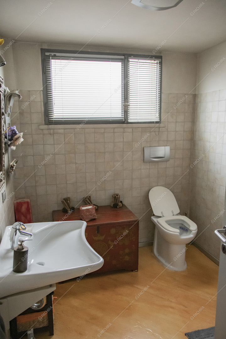 Bagno con pavimento in parquet, pistrelle alle pareti bianche e finestra