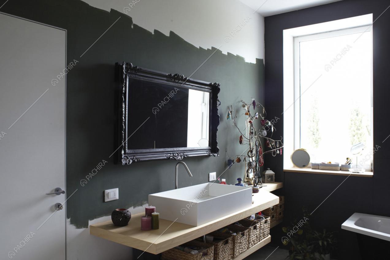 Pareti nere e specchio con cornice decorata nel bagno