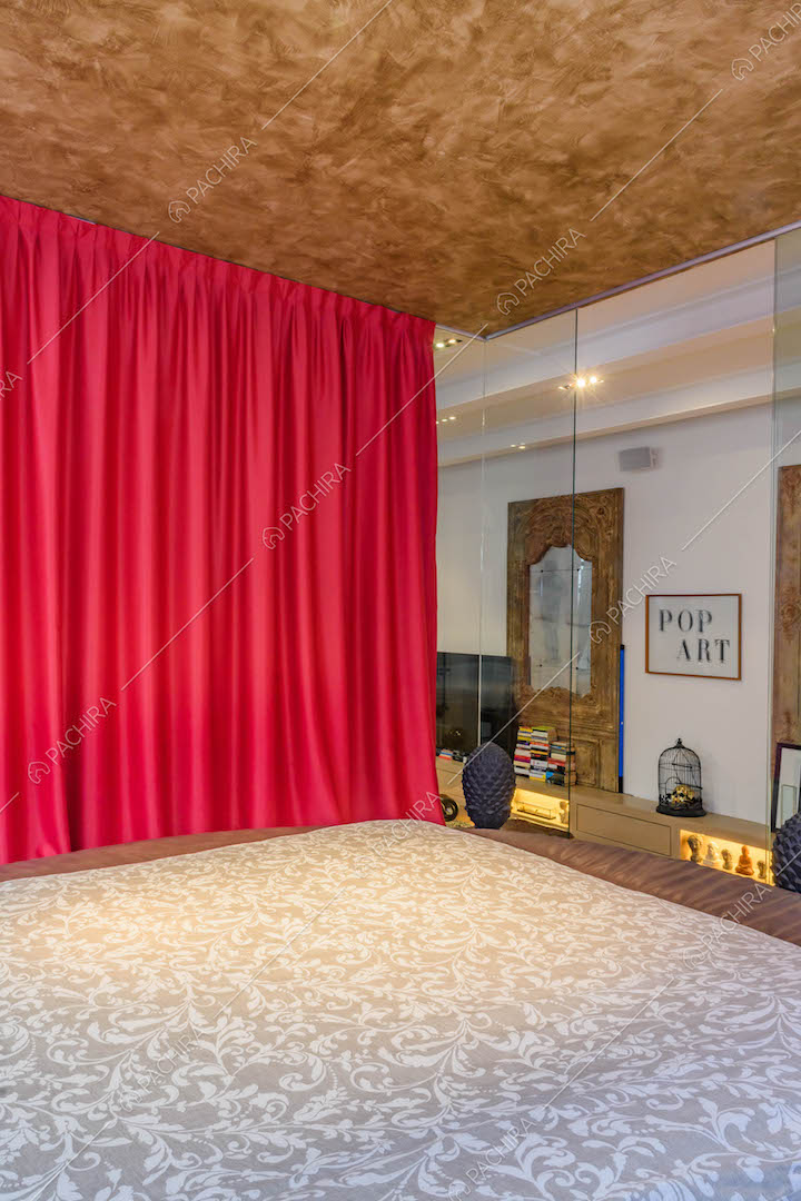 Letto matrimoniale nella camera con tenda fucsia e pareti in vetro