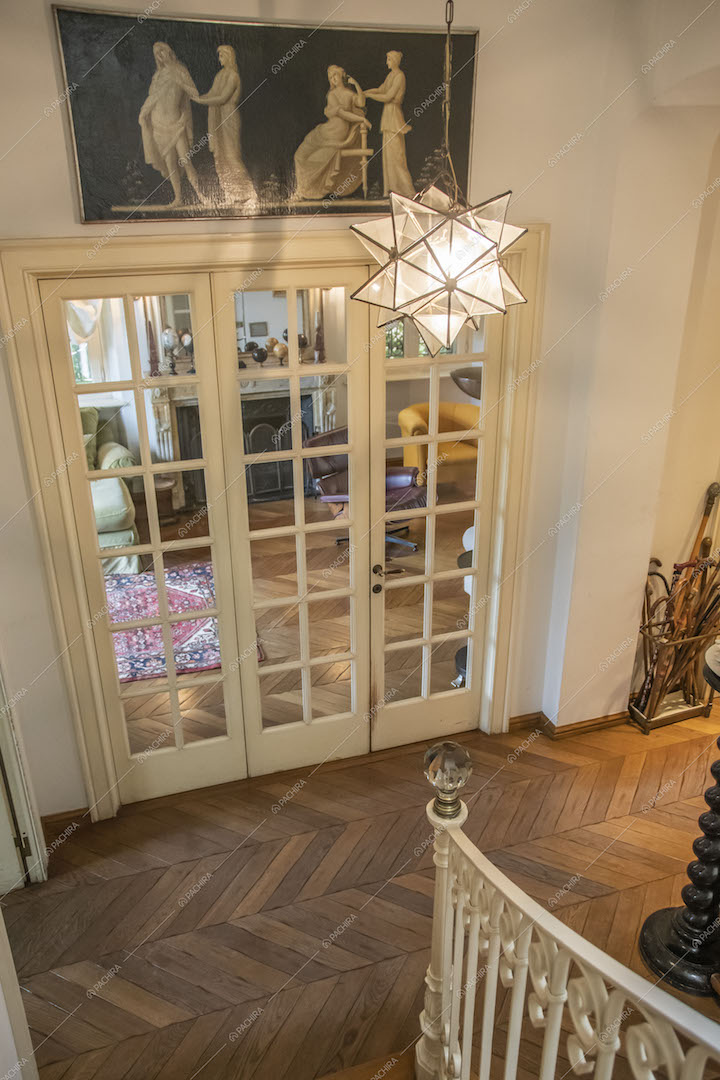 Dalle scale vista sull'atrio con pavimento in parquet a spina di pesce tramite la porta a vetri