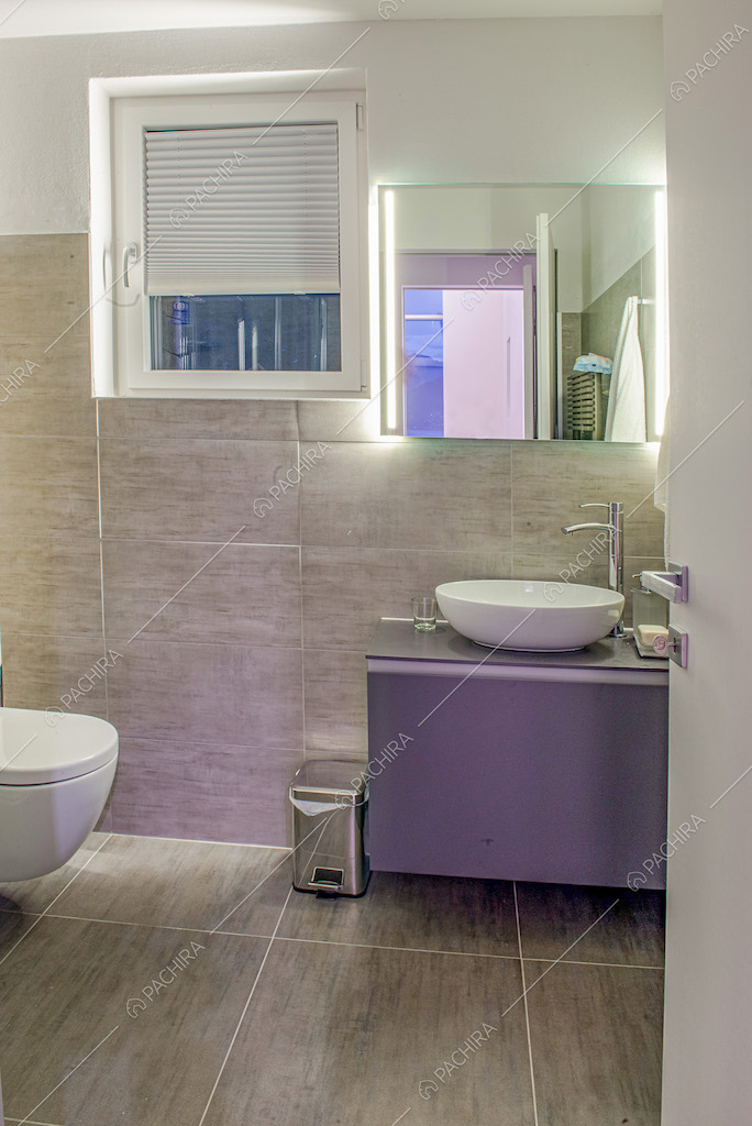 Bagno con mobile sospeso e piastrelle grigie
