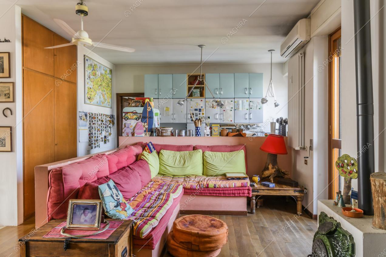 Salotto con divano, cucina a vista e pavimento in parquet