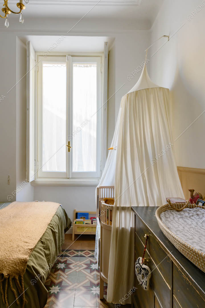 Luminosa camera da letto matrimoniale con culla e pavimento in graniglia a mosaico