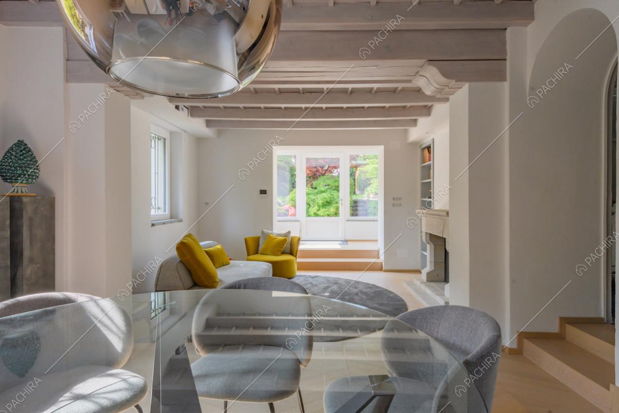 Tavolo da pranzo e sedie grigie nel salotto con pavimento in parquet e camino
