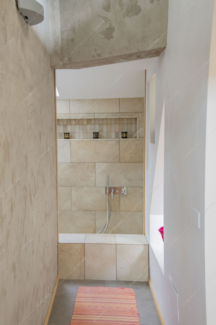 Corridoio che conduce al bagno con vasca e parete in lastre di pietra