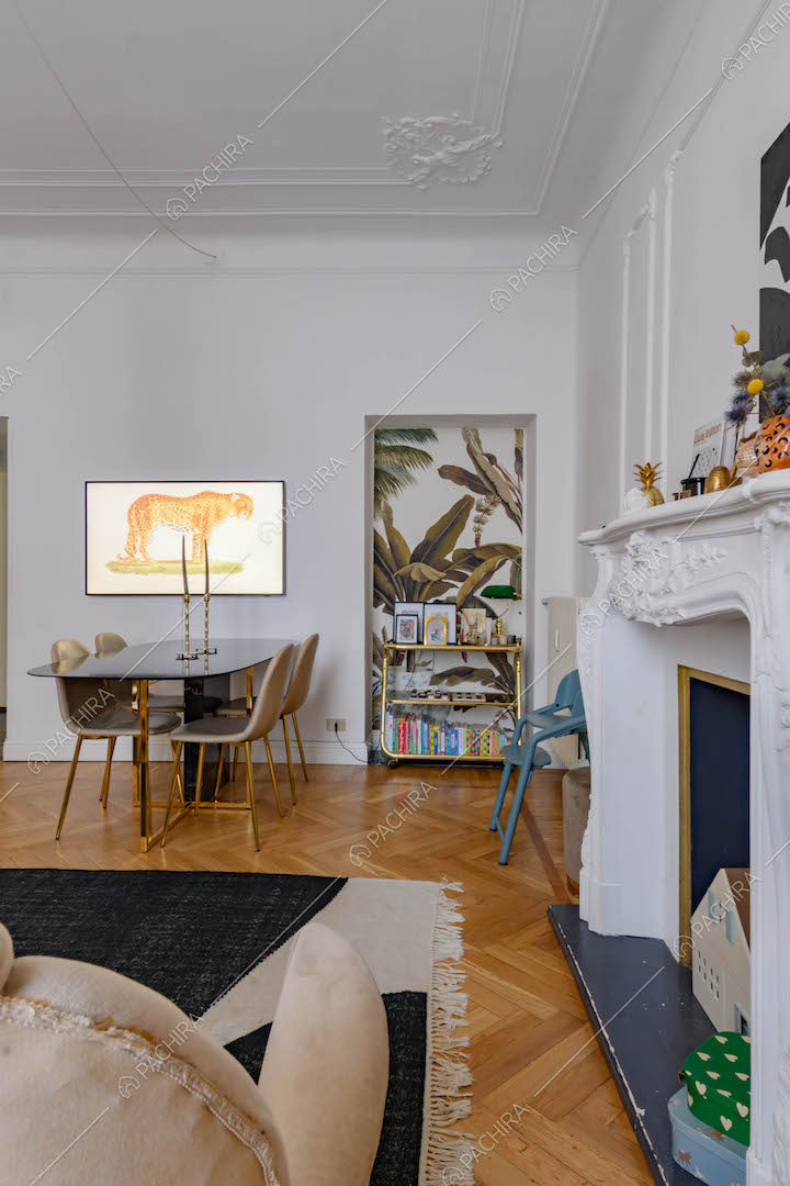 Divano accanto al camino, pavimento in parquet a spina di pesce e boiserie sul soffitto
