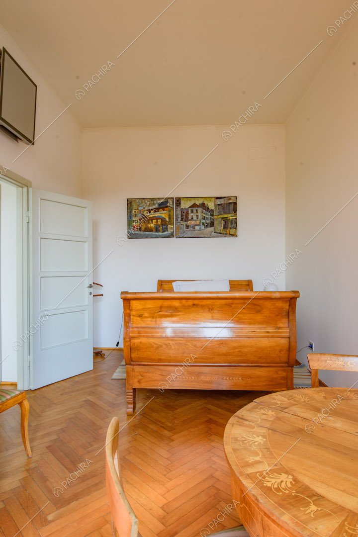 Tavolo in legno nella luminosa camera da letto con pavimento in parquet a spina di pesce