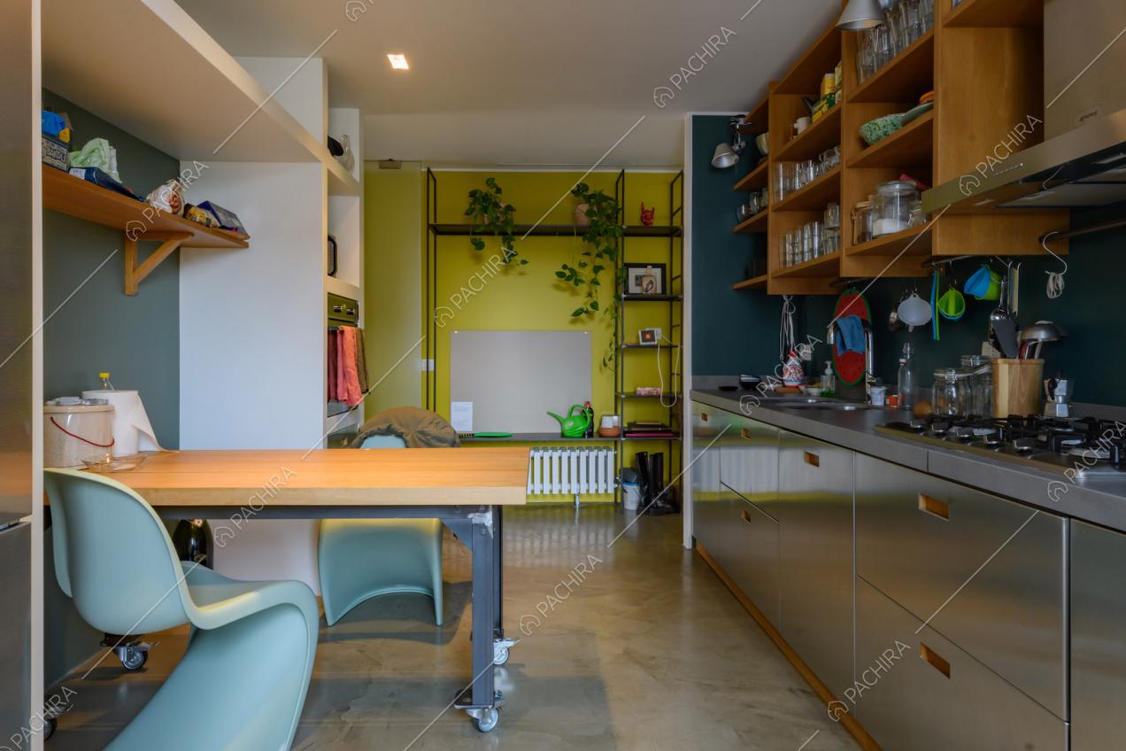 Tavolo in legno con rotelle nella cucina a parete in acciaio e con fornelli a gas