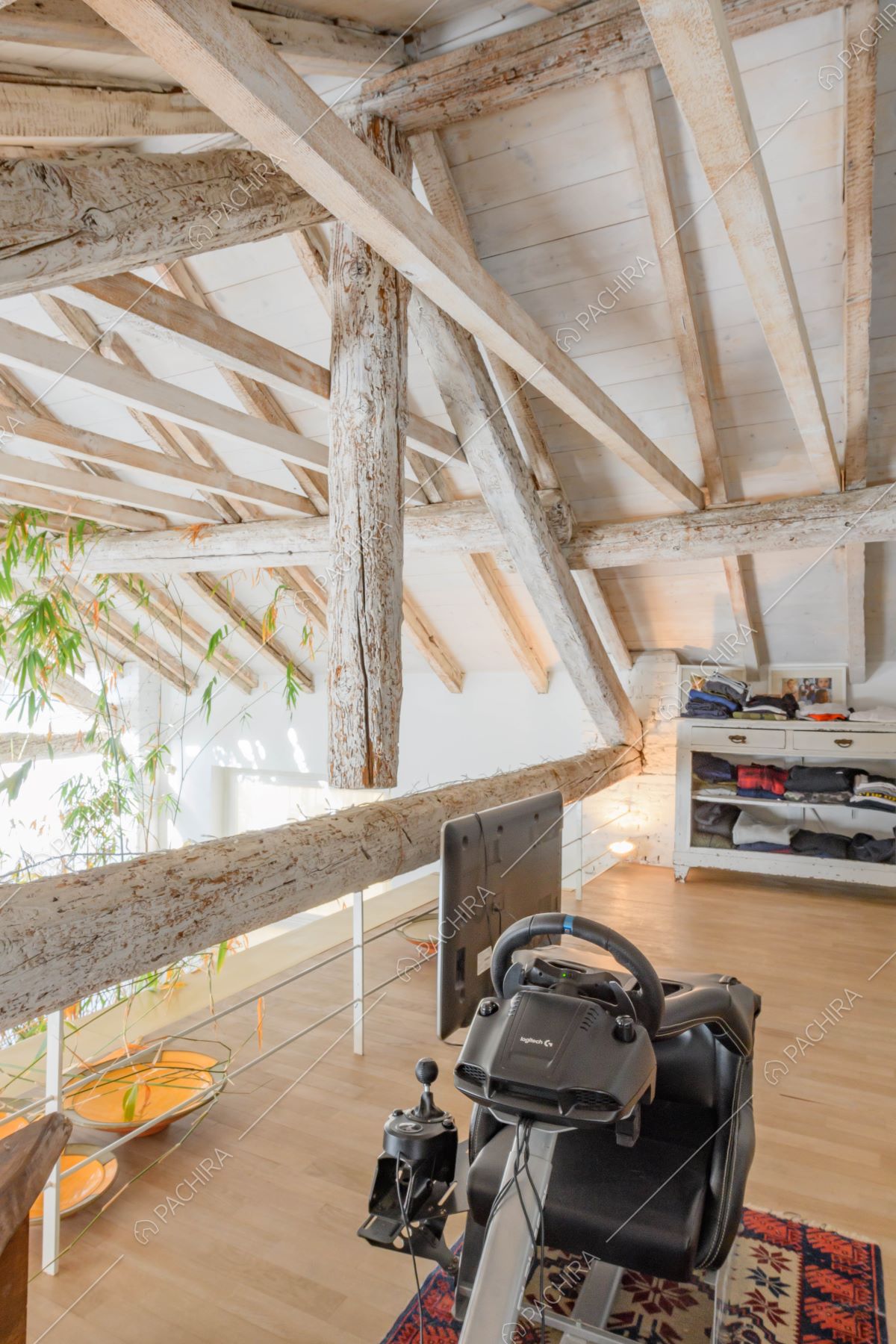 Camera da letto sul soppalco con travi in legno a vista sul soffitto e pavimento in parquet
