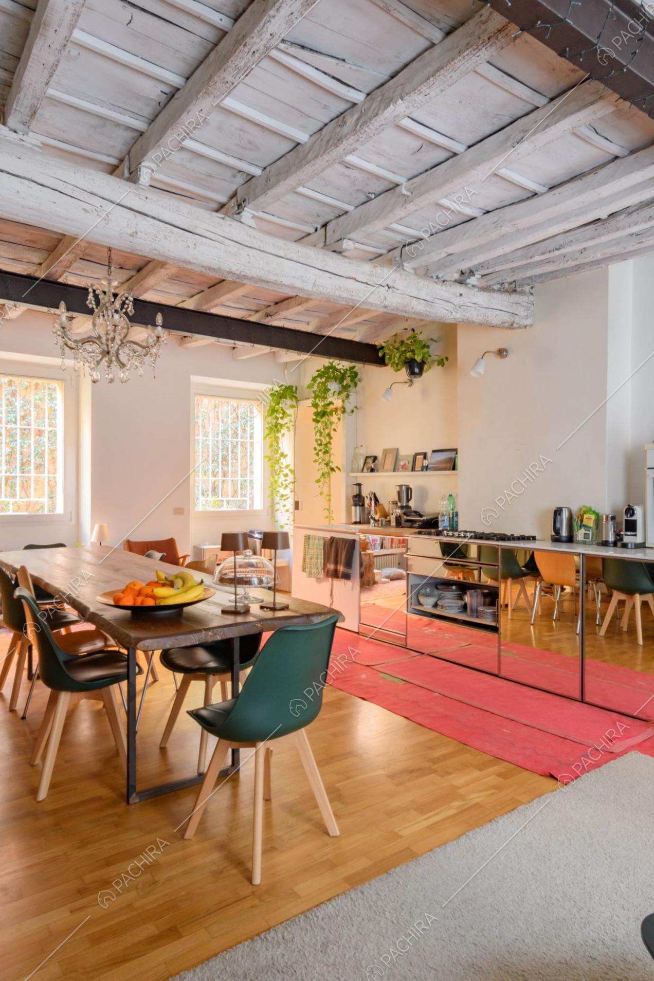 Tavolo da pranzo, lampadario e cucina a parete con fornelli a gas
