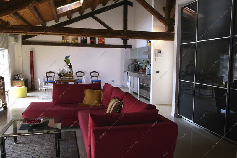 Divano rosso angolare, soffitto con travi a vista e lucernario