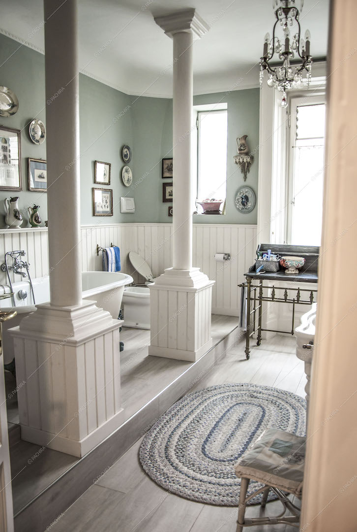 Bagno con vasca su piano rialzato e colonne bianche