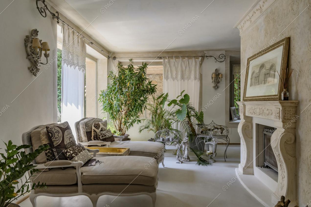 Sala con pavimento in cemento lisciato, pareti bianche e camino con boiserie