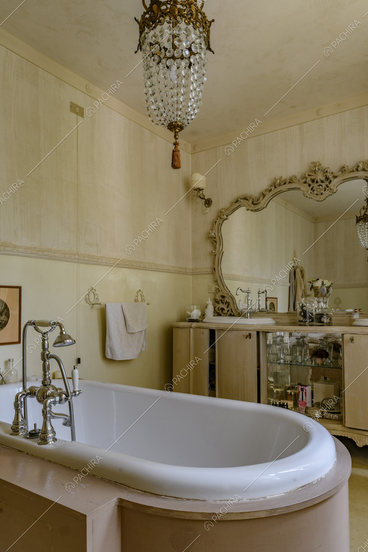 Bagno con vasca, specchio con cornice dorata e lavorata e carta da parati