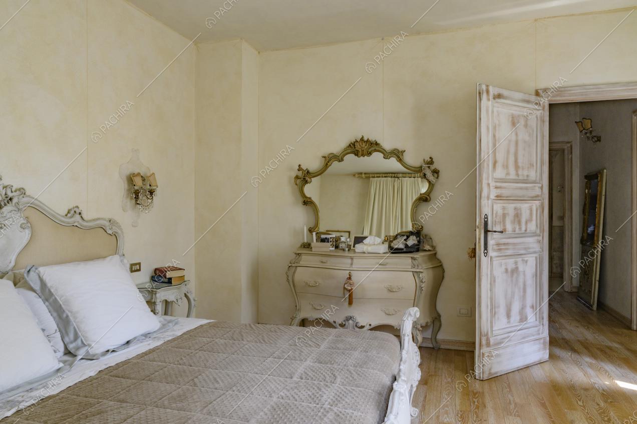 Camera da letto matrimoniale dalle pareti color crema e dal pavimento in parquet