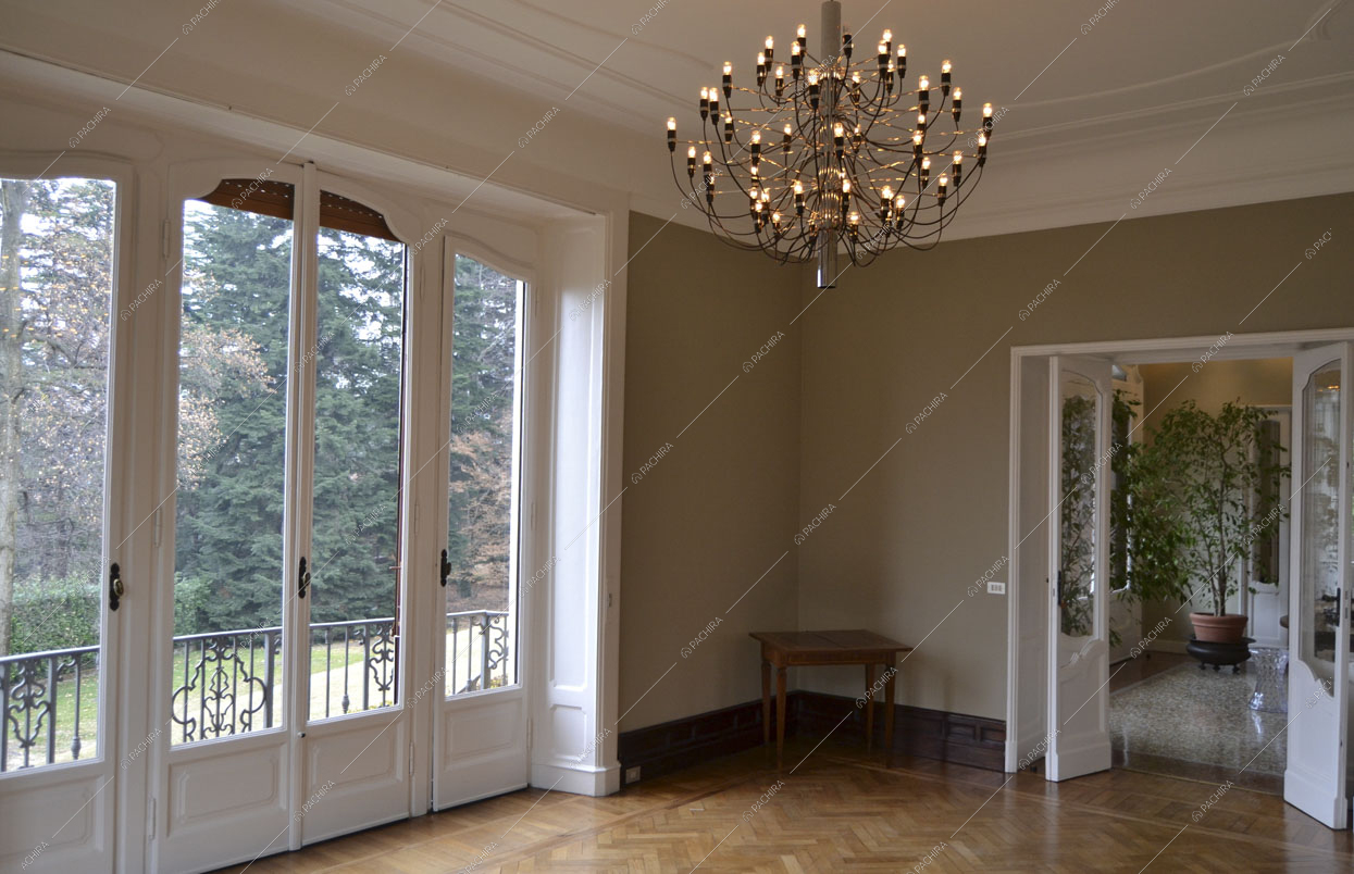 Salone con porte-finestre che portano al balcone, con pareti beige e boiserie sul soffitto bianco