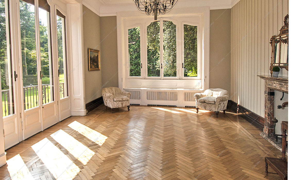 Luminoso salone con parquet a spina di pesce, porte finestre in stile classico e camino