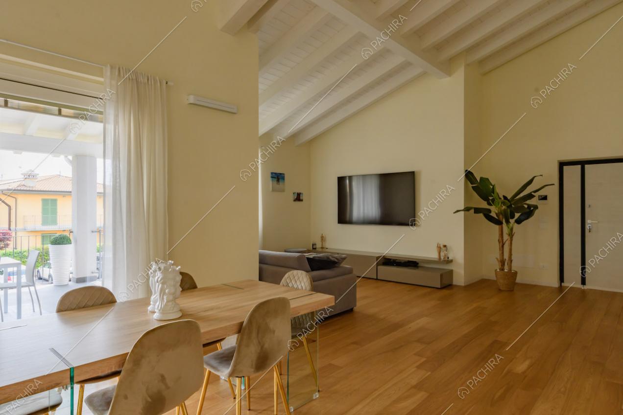 Travi bianche a vista sul soffitto, tavolo da pranzo e pavimento in parquet nella zona living