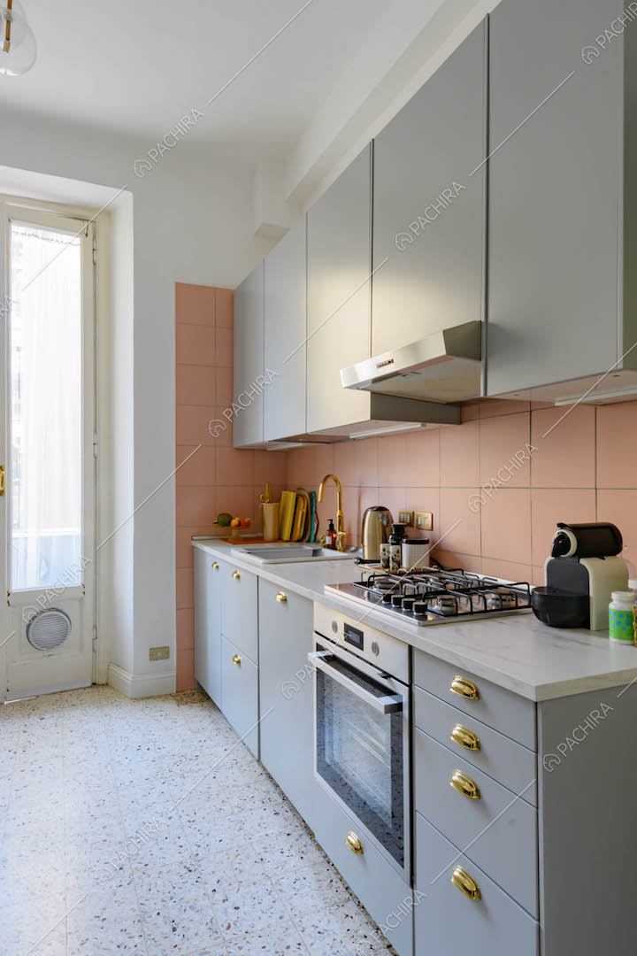 Cucina con porta-finestra, parete e paraschizzi in piastrelle rosa e fornelli a gas