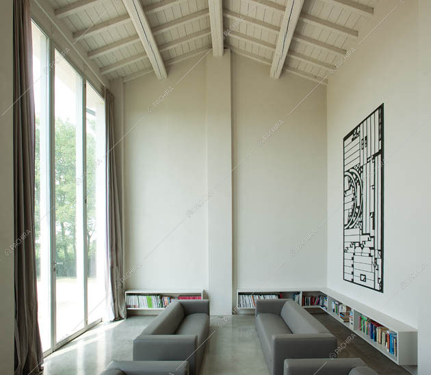 Zona living con divani grigi e soffitto alto