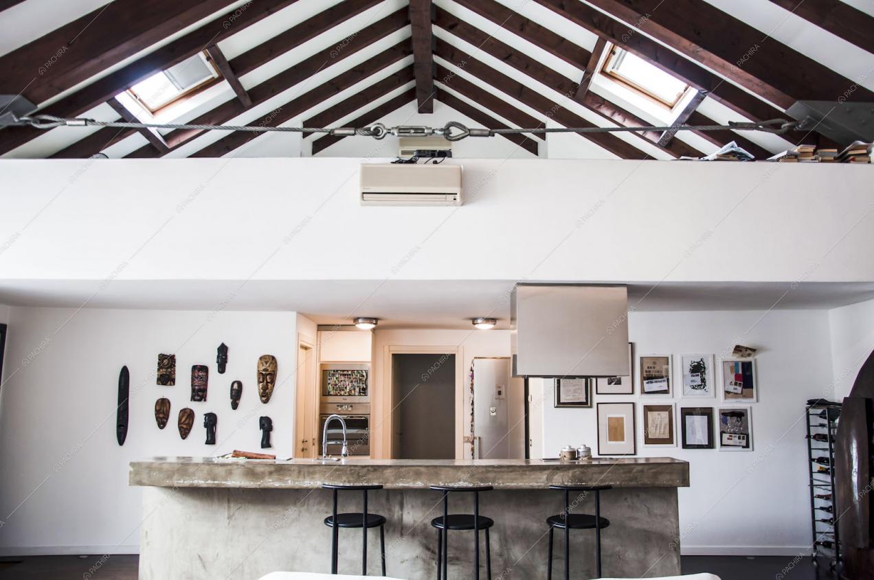 Vista della cucina, sgabelli neri, soffitto con travi a vista