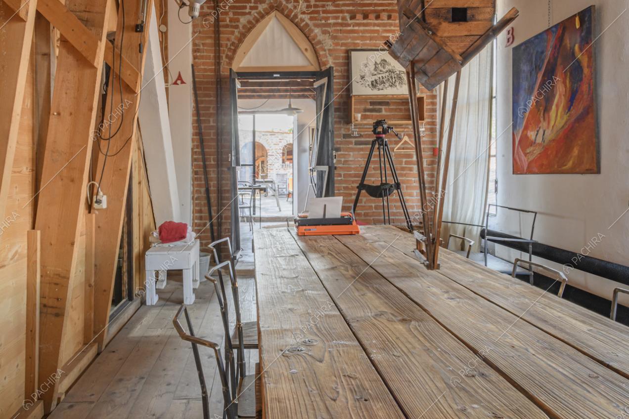 Lungo tavolo in legno e parete con mattoni a vista