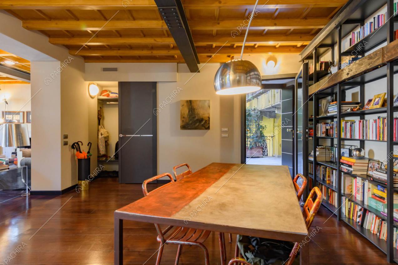 Dal tavolo da pranzo nella sala con travi in legno a vista sul soffitto scorcio sul cortile interno