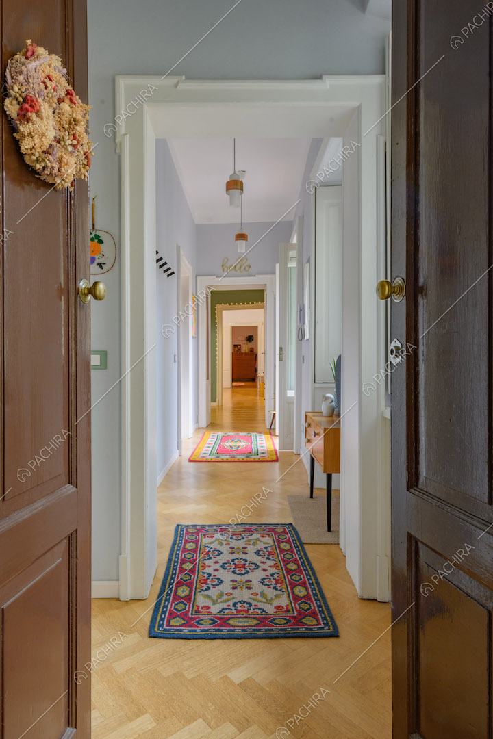 Dalla porta d'ingresso vista sul lungo corridoio con pavimento in parquet a spina di pesce