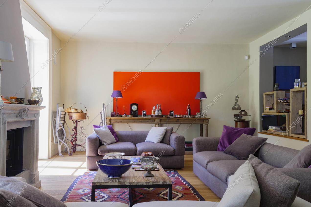 Salotto della villa con divani viola, camino e pavimento in parquet
