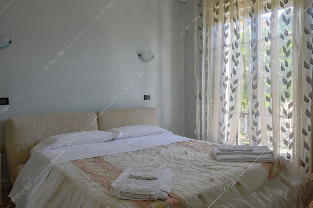Letto matrimoniale e porta finestra con tende decorate