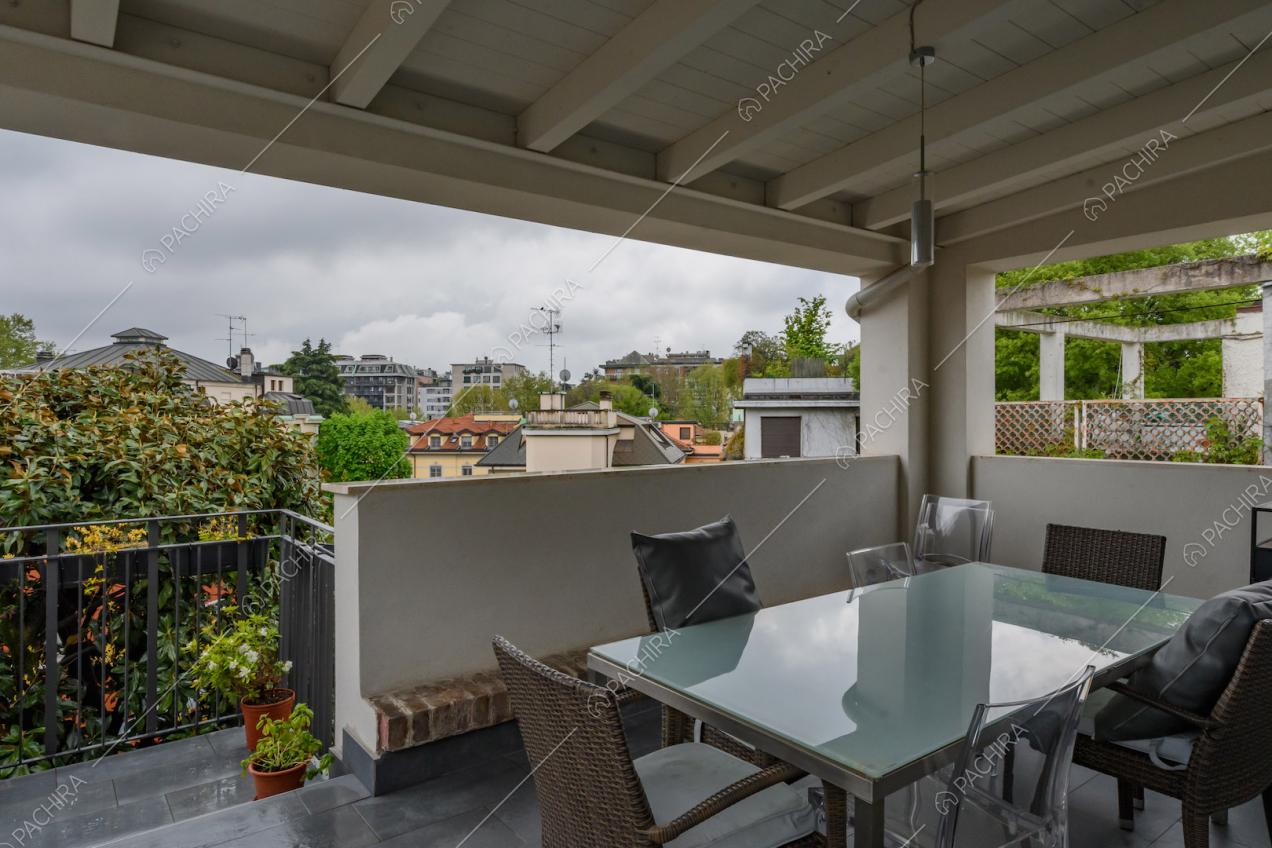 Terrazza coperta con soffitto in travi bianche a vista e tavolo da pranzo