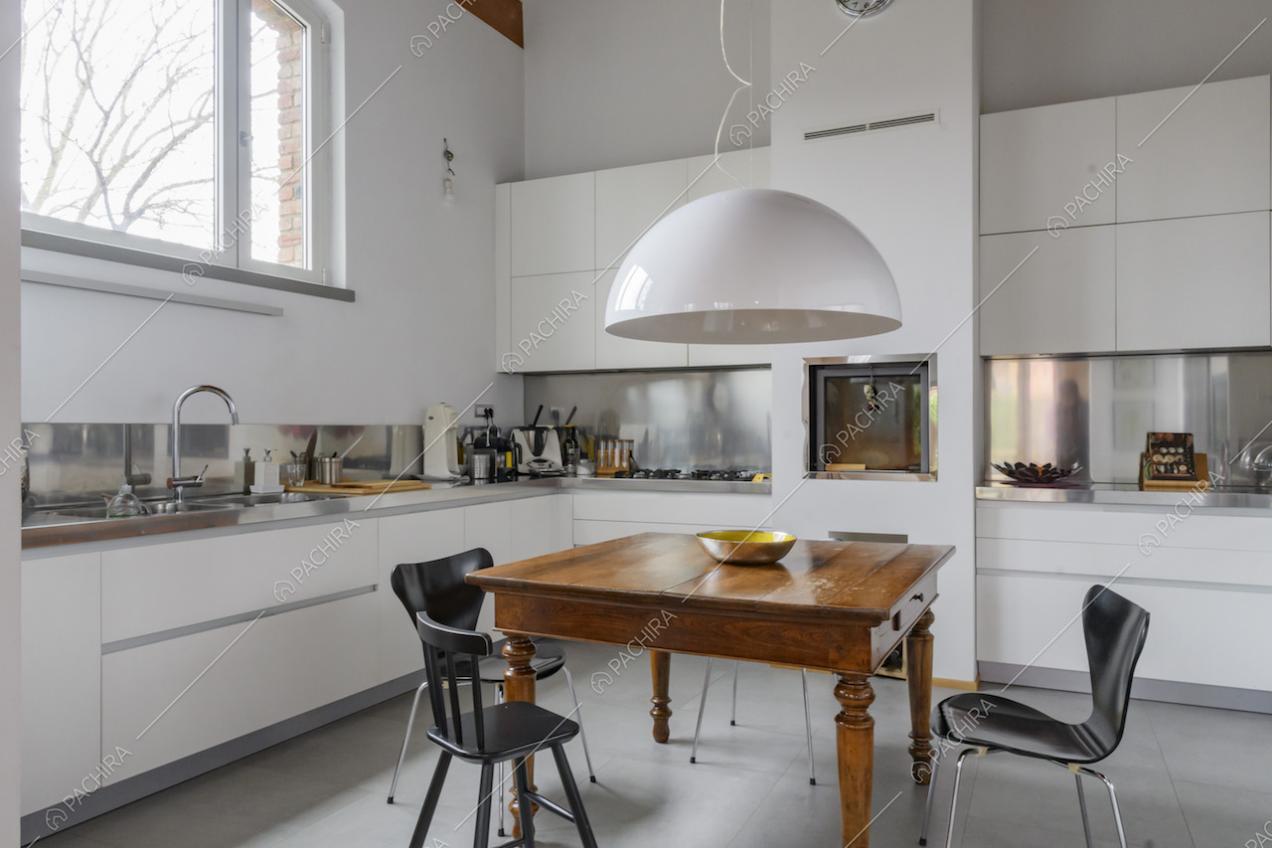 Luminosa cucina bianca a parete con fornelli a gas e lampadario bianco di design