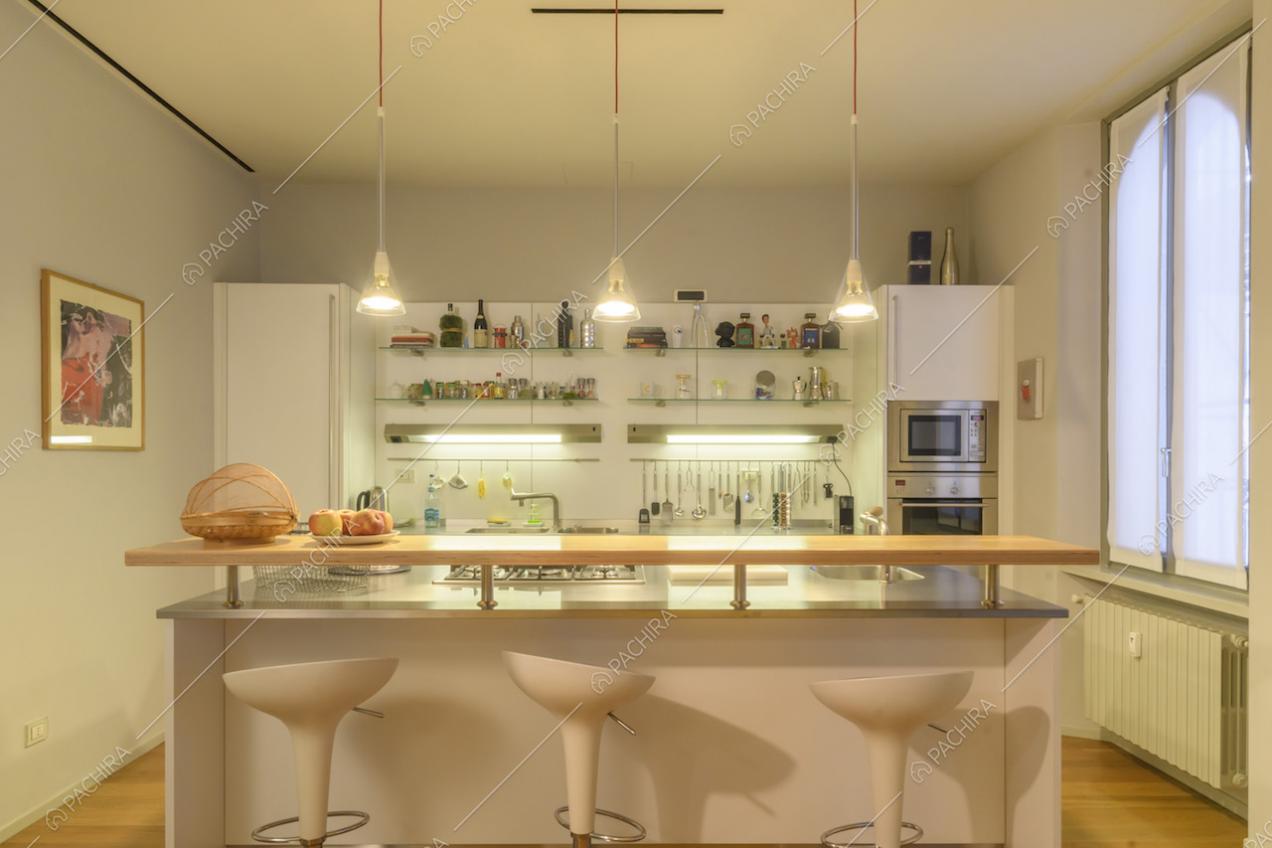 Cucina a isola con sgabelli bianchi e lampade di design