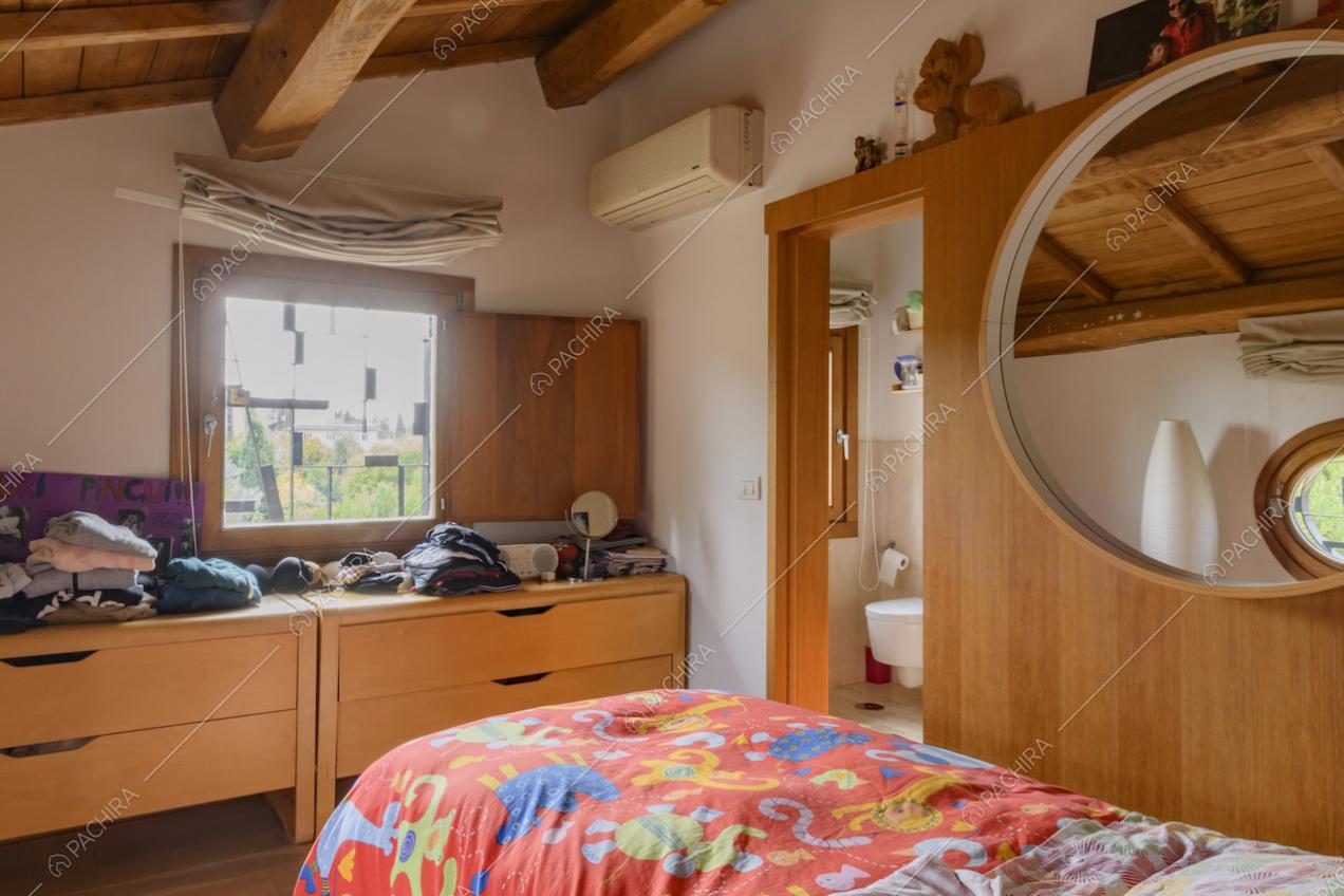 Camera da letto con arredi in legno, specchio tondo e bagno
