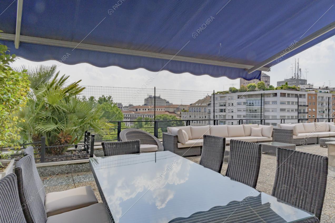 Tavolo da pranzo e divani da esterno sull'ampia terrazza con vista panoramica su Milano