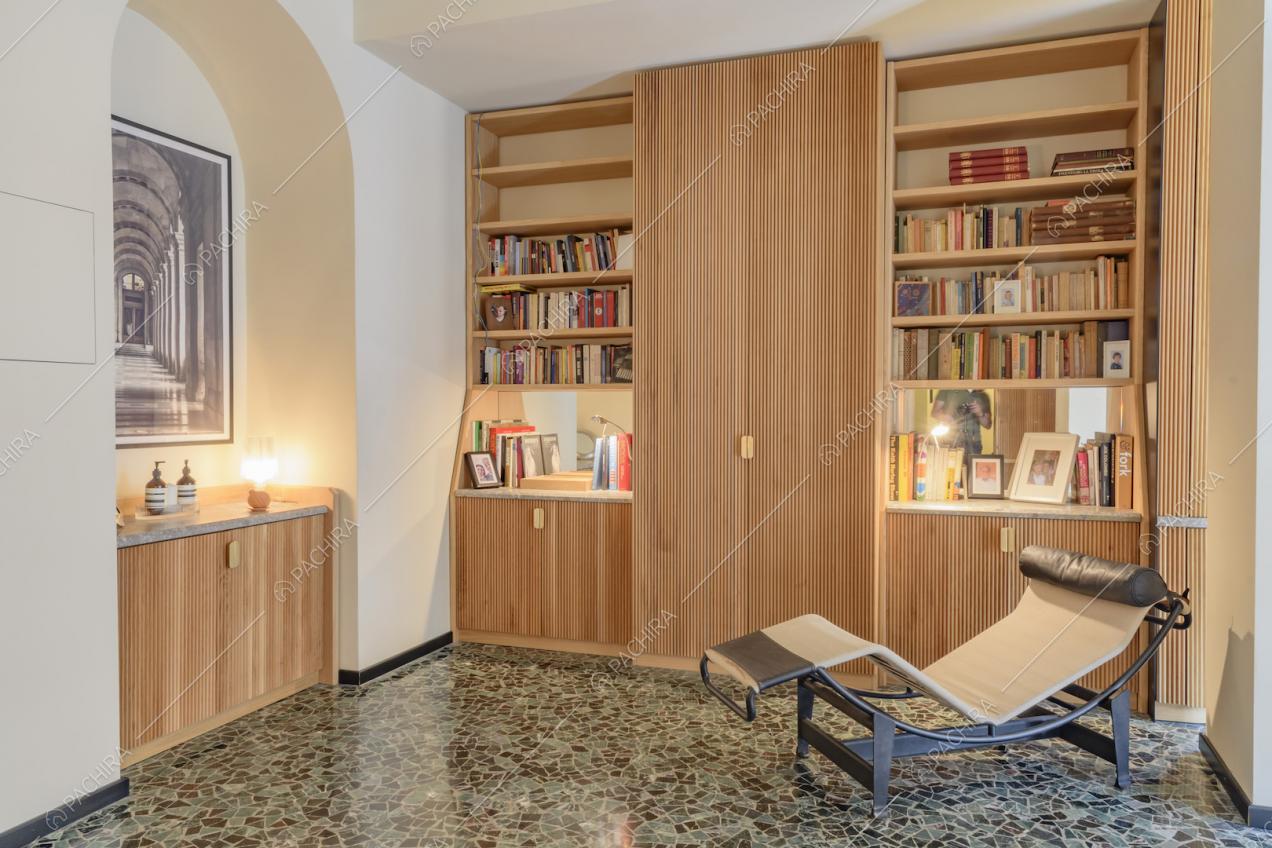 Poltrona di design nella stanza dal pavimento in marmo e con libreria a parete