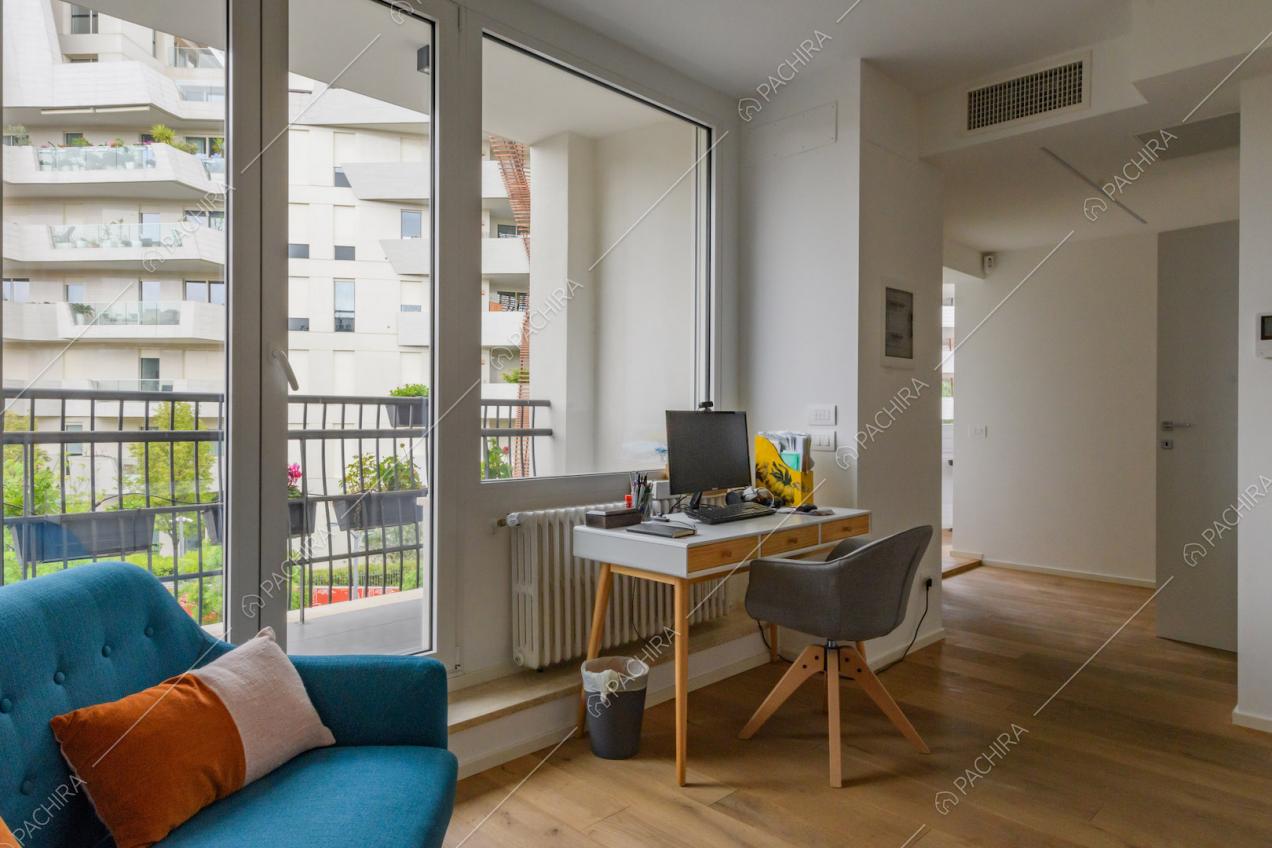Pavimento in parquet nel luminoso salotto con scrivania e porta-finestra