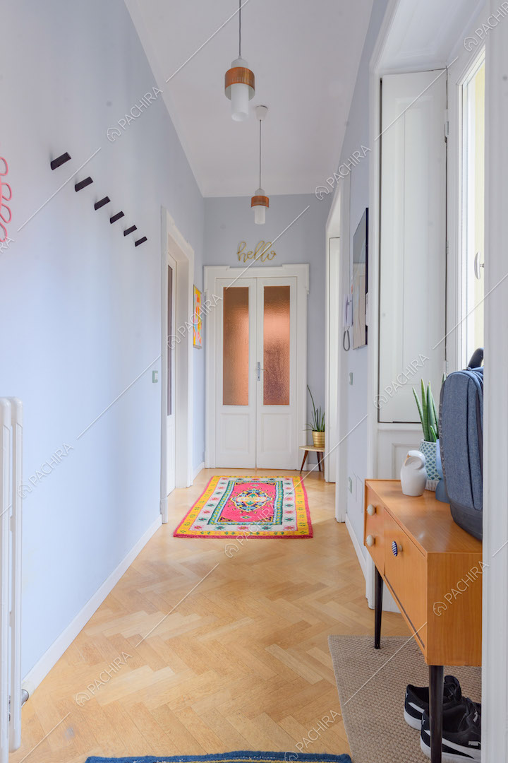 Luminoso corridoio con pareti azzurre e pavimento in parquet a spina di pesce