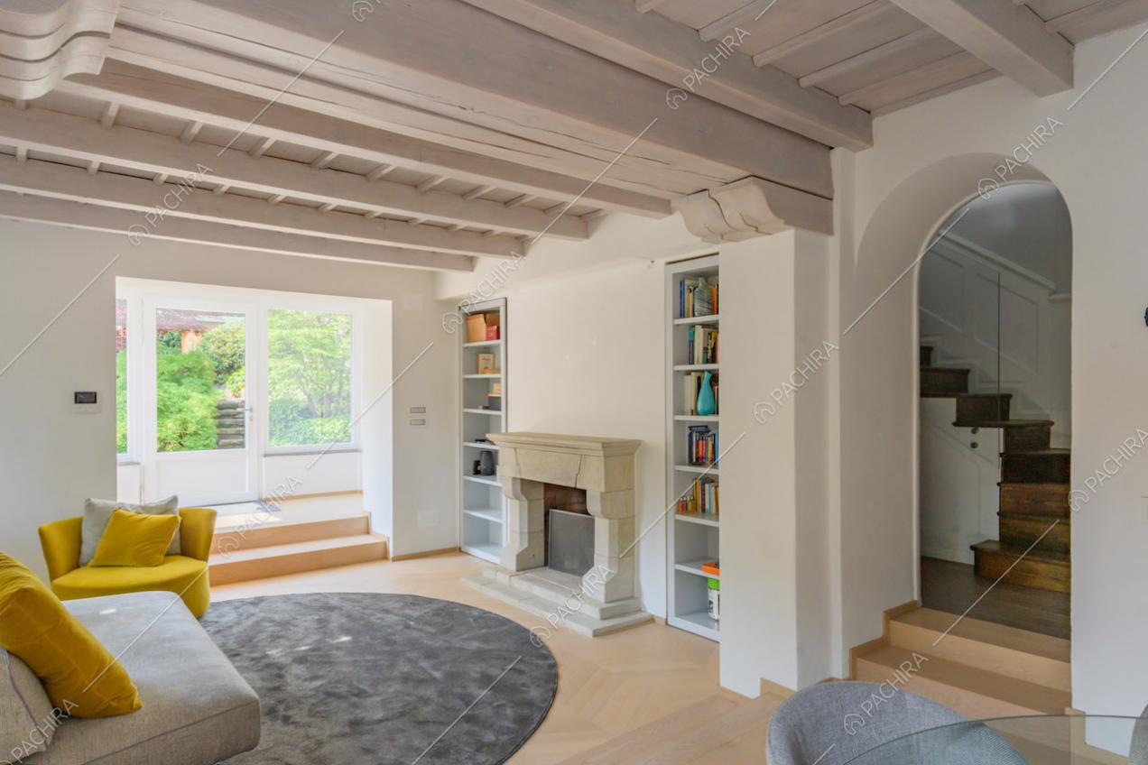 Grande salotto con camino, pavimento in parquet e soffitto in travi in legno a vista