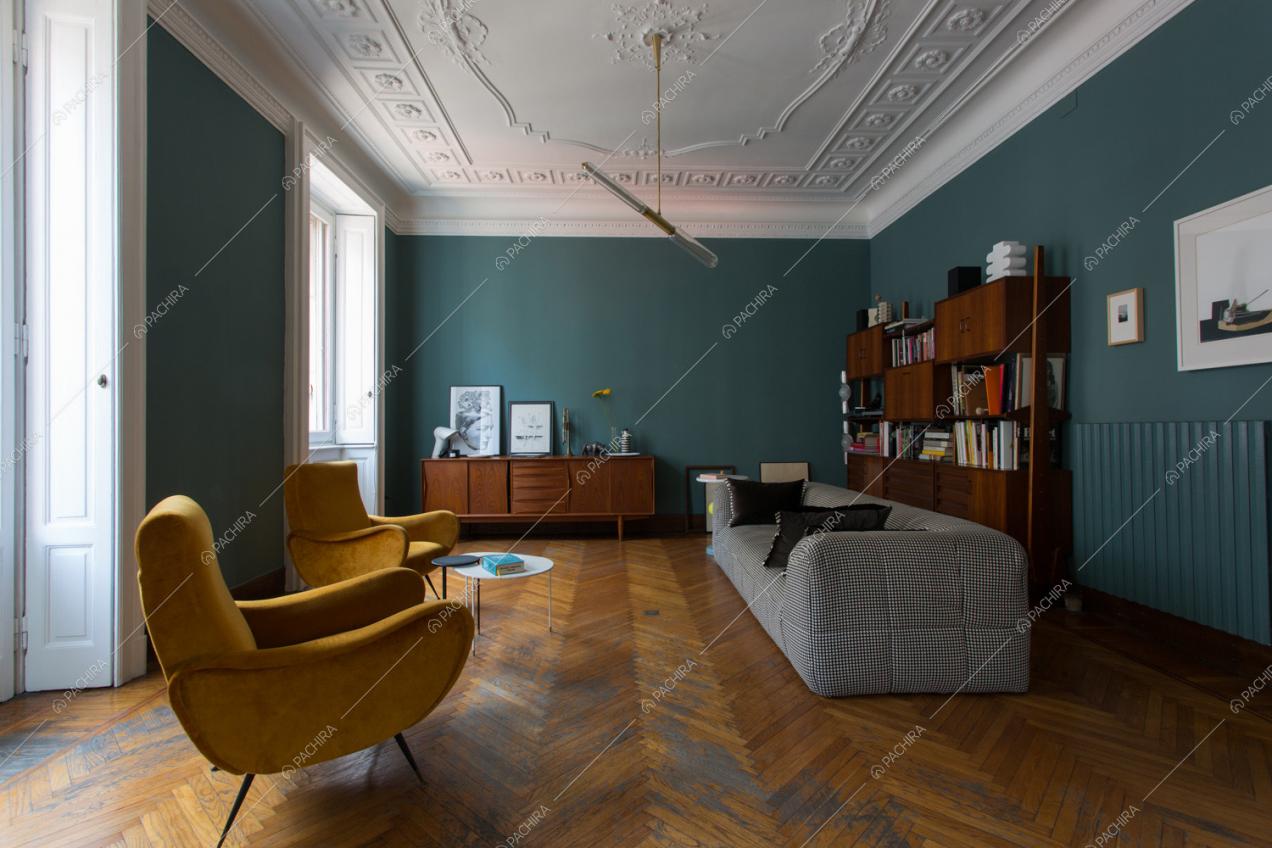 Pareti blu petrolio e soffitto con boiserie nel soggiorno