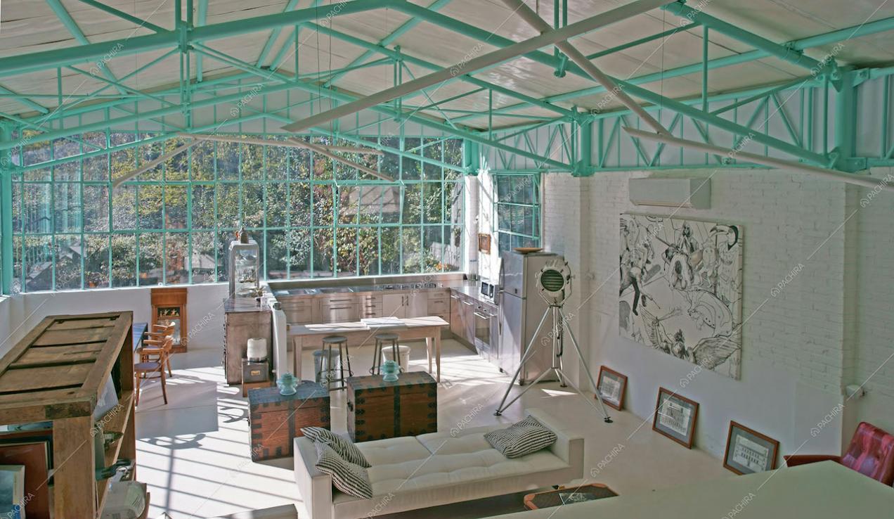 Open space con ampie vetrate e travi verdeacqua in metallo
